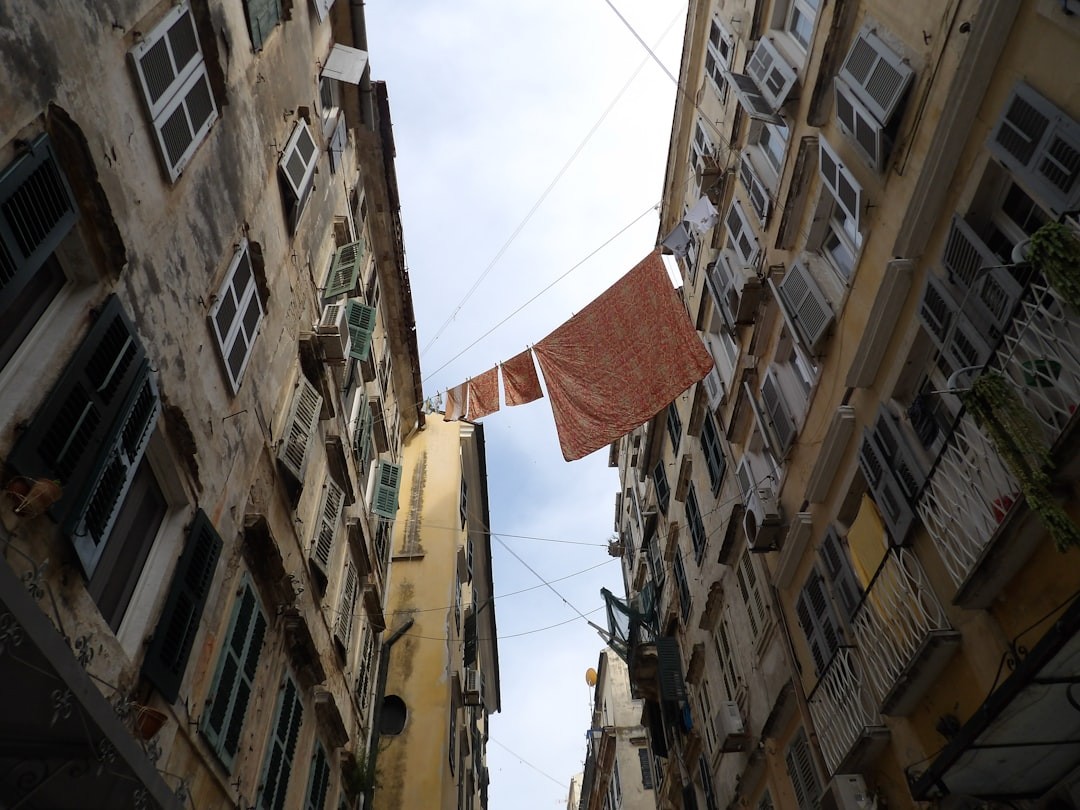 Narrow alley between two tall, aged buildings with laundry hanging on lines stretching across the gap.